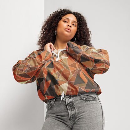 Woman wearing a cropped multicolor geometric patterned windbreaker jacket and gray jeans against a plain background