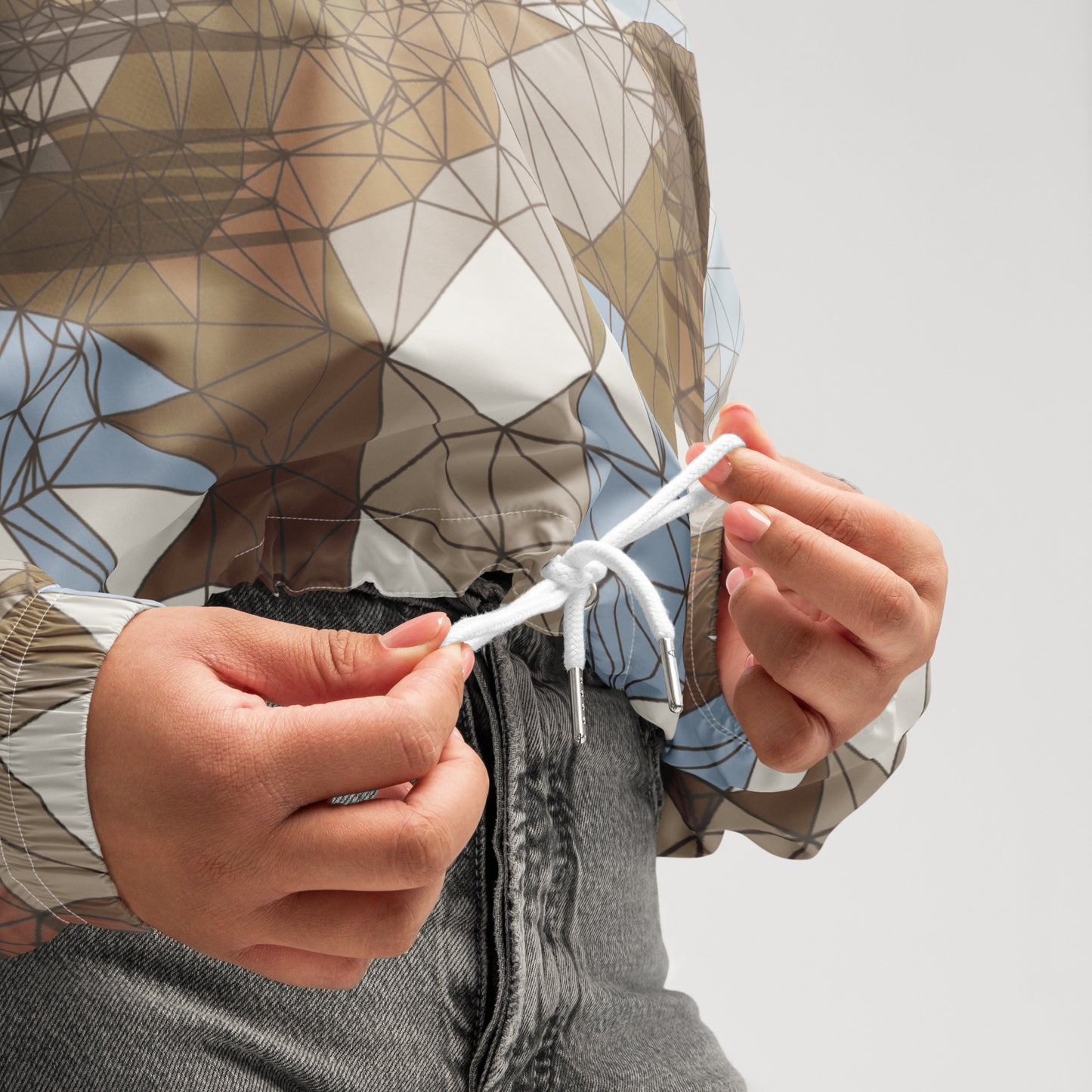 Person tying a knot with a geometric-patterned fabric head covering on a plain background