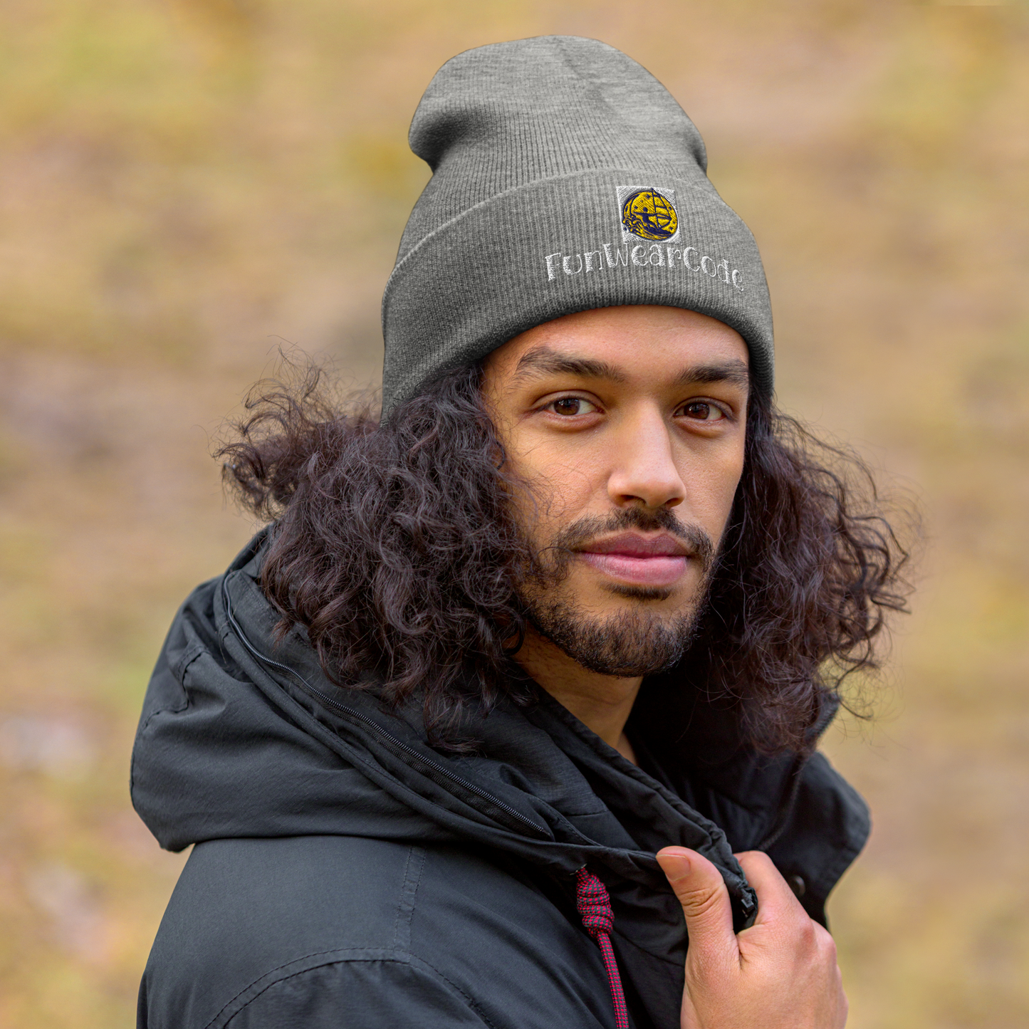 Man wearing a gray beanie with a FunWearCode logo and text, standing outdoors with a blurred natural background.