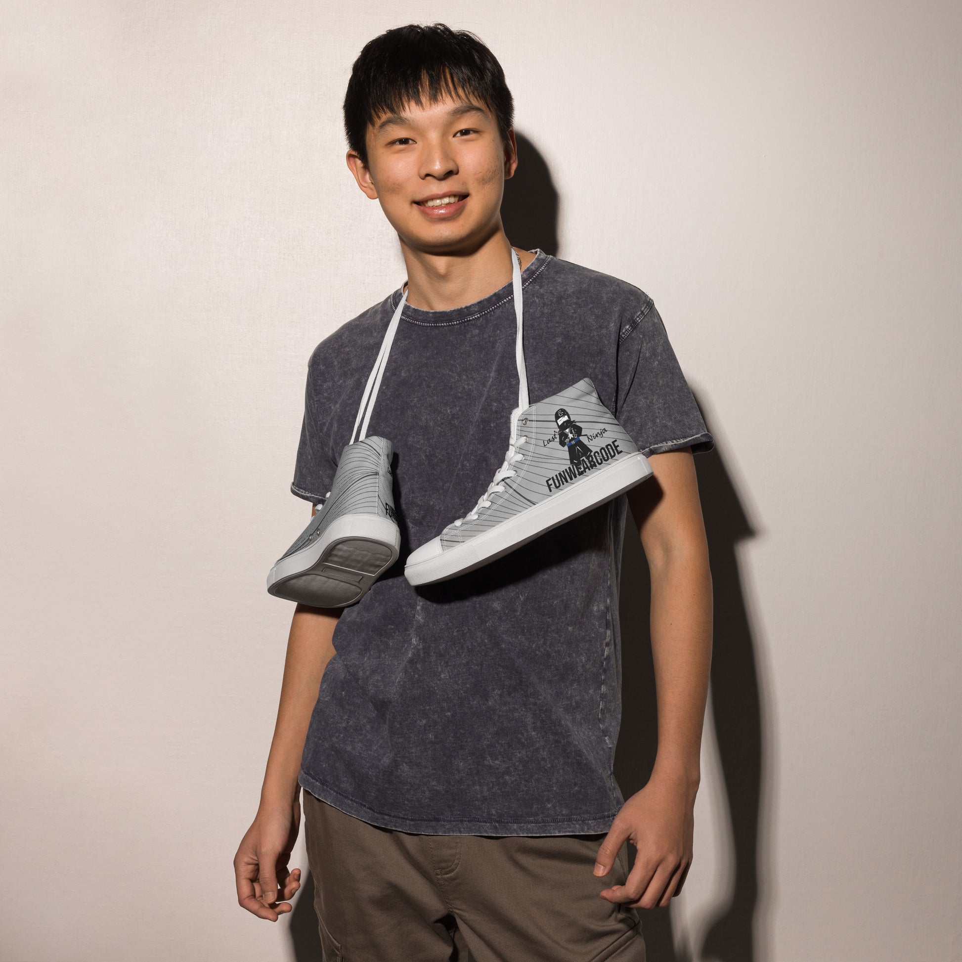Person holding two sneakers with a ninja graphic and 'Fun Wear Code' text logo against a plain background