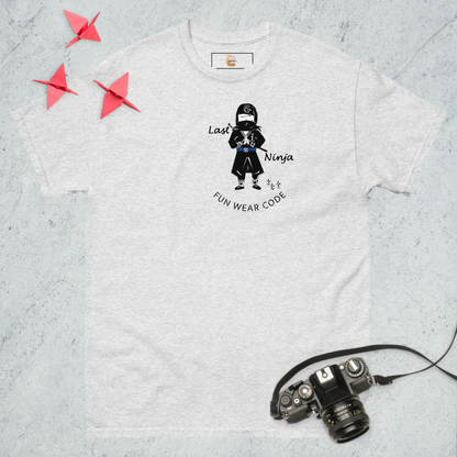 Ash gray t-shirt with a playful ninja graphic design and text "FUN WEAR CODE", placed on a textured surface with a camera and origami birds.