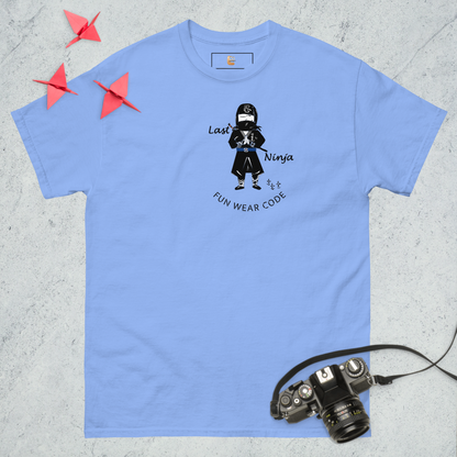 Blue t-shirt with a playful ninja graphic design and text "FUN WEAR CODE", placed on a textured surface with a camera and origami birds.